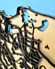 Macro detail of San Juan Puerto Rico framed 3D city map, precision laser-cut wood layers, raised street pattern, black wooden frame, white mat border and engraved location coordinates
