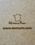 Extreme close-up of laser engraving on natural oak wood showing “Fait main en France” and www.demurin.com on the back of a San Juan 3D city map frame, showcasing premium handcrafted quality.