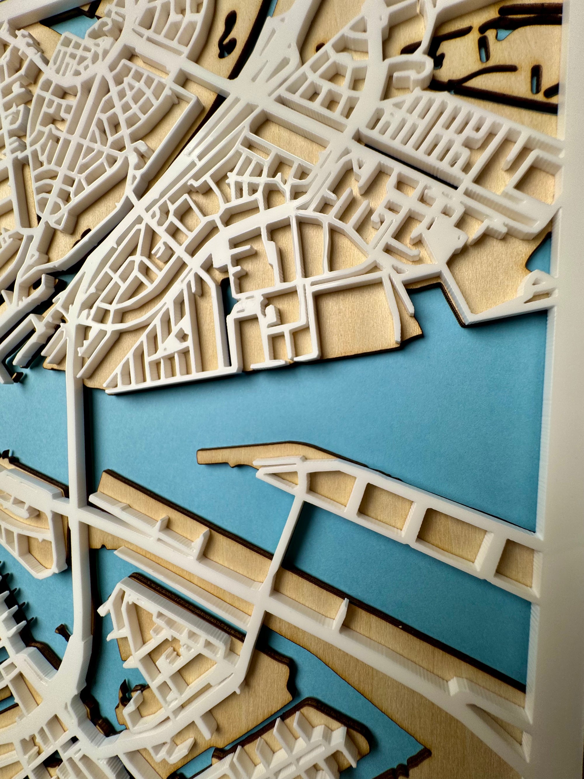 Close-up of Amsterdam city map wall art showing intricate laser-cut wooden street details and blue canals – handcrafted Amsterdam map artwork with layered design for modern wall decor
