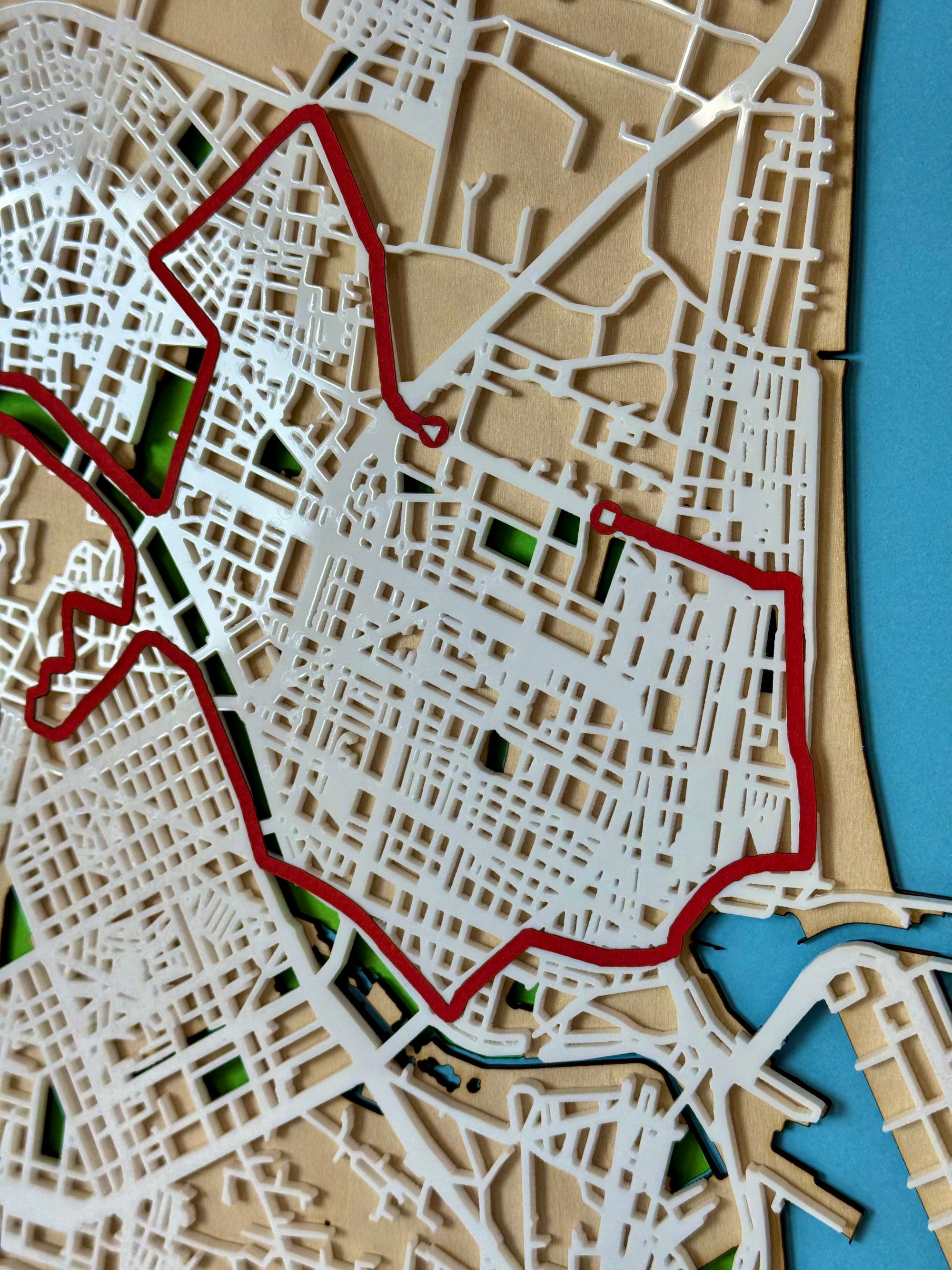 Close-up detail of a personalized marathon route map showing layered wood streets and red race course line, precision laser-cut design.