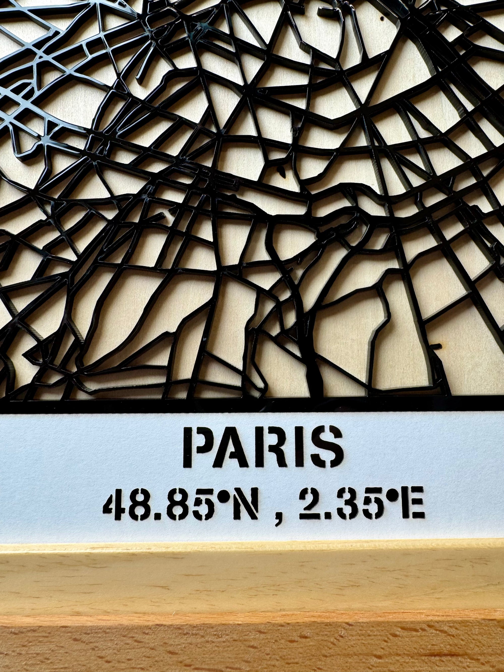 Close-up of personalized Paris city map wall art showing engraved “Paris” title and geographic coordinates, detailed laser-cut wooden city map artwork with layered design for modern home decor