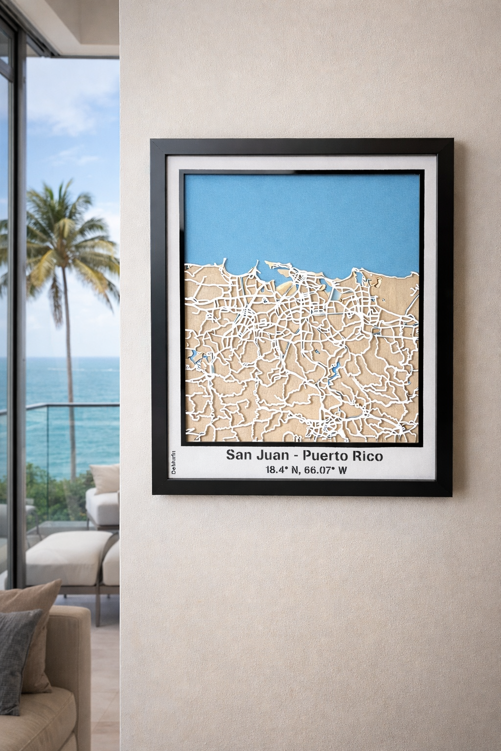 San Juan Puerto Rico framed 3D city map featuring white precision laser-cut street network, natural wood layers and blue ocean detail, showcased in a modern living room with sea view.