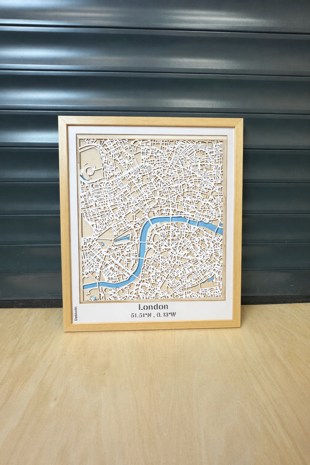 London white street 3D city map wall decor in natural wood frame – detailed multi-layer laser-cut road network in white over light wood backing with blue River Thames accent, handcrafted in France.